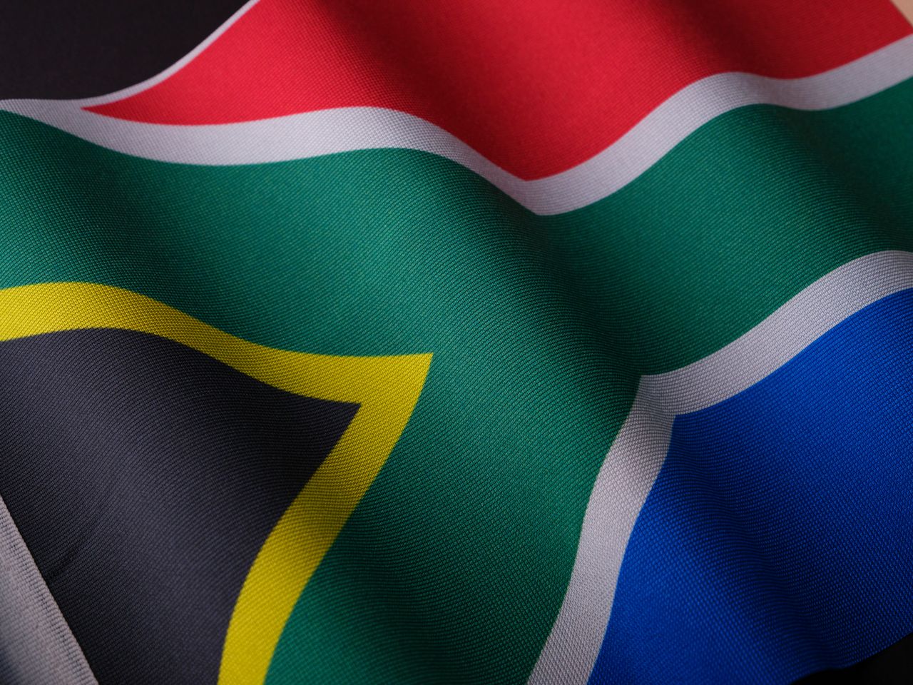 services-01 Close-up of a waving South African flag showcasing its vibrant colors and detailed texture.
