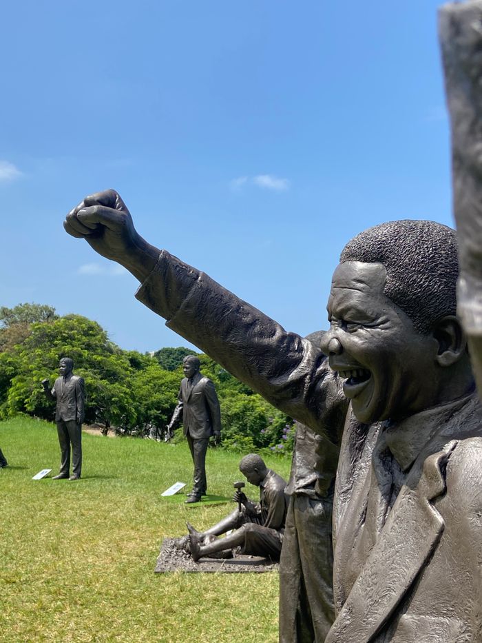 our-story Bronze statues of Nelson Mandela in Berea Park, showcasing iconic poses outdoors.